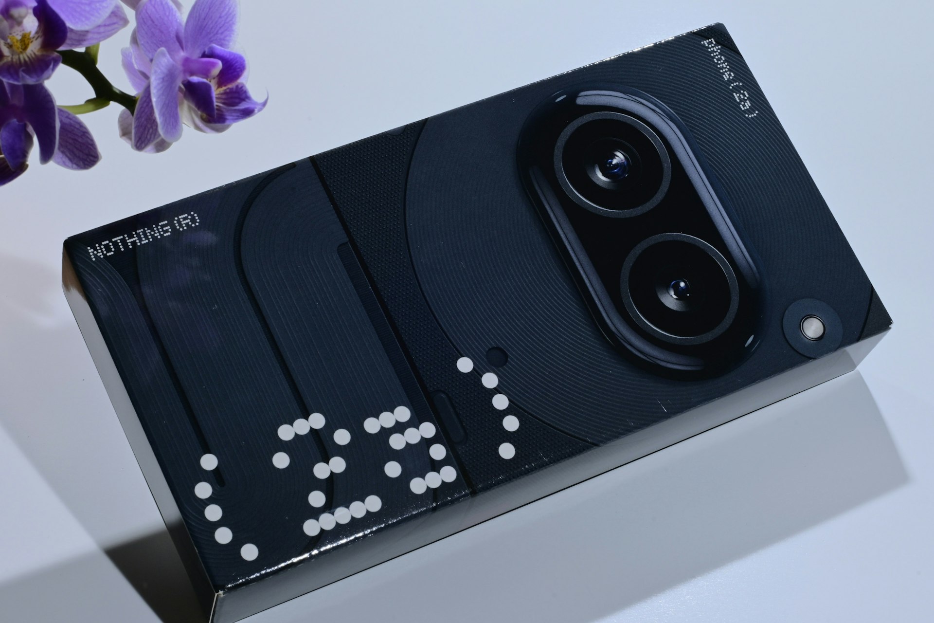 A camera sitting on top of a table next to a purple flower
