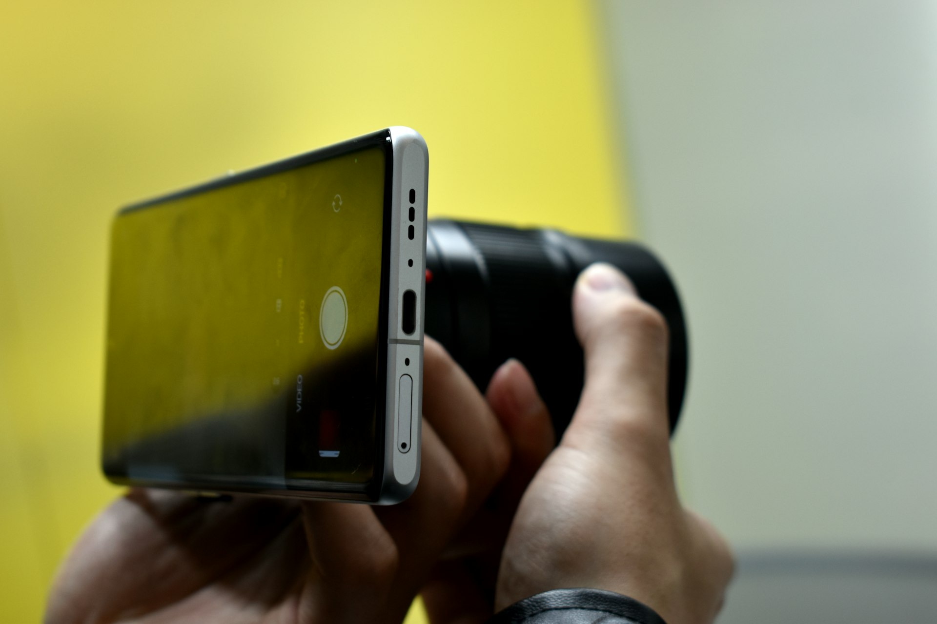 Hands holding a smartphone and camera lens